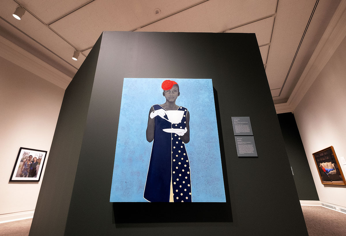 A painting of a woman in a blue dress and red hat at Ackland.